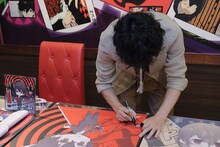 テーブルにサインをする福山潤。