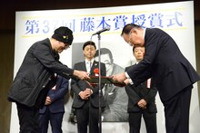 賞状を受け取る青山剛昌（左）。