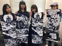 石ノ森章太郎生誕80年記念で制作された手ぬぐいを手にする女性たち。