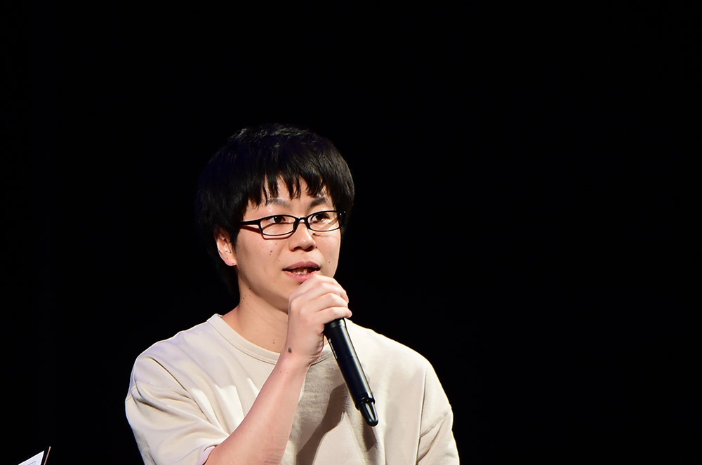 「グリムノーツ」ステージの模様。原作ゲームのプロデューサー・石井諒太郎。(c)SQUARE ENIX/グリムノーツ The Animation製作委員会・TBS(c)2016 - 2018 SQUARE ENIX CO.,LTD. All Rights Reserved.