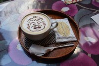 美術館に隣接する「夢二カフェ 港や」ではコラボメニュー「万作カプチーノ」を提供中。カプチーノの絵柄はランダムで全4種が用意されており、中でも悠理のデザインは本商品のために一条が描き下ろしたイラストを使用している。