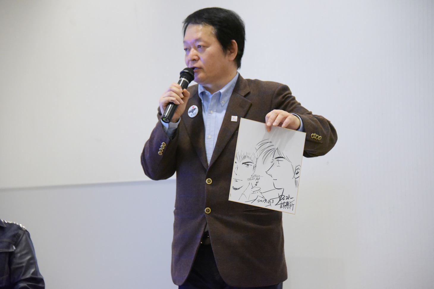 藤沢とおるとの合作した色紙を手にする山田貴敏。
