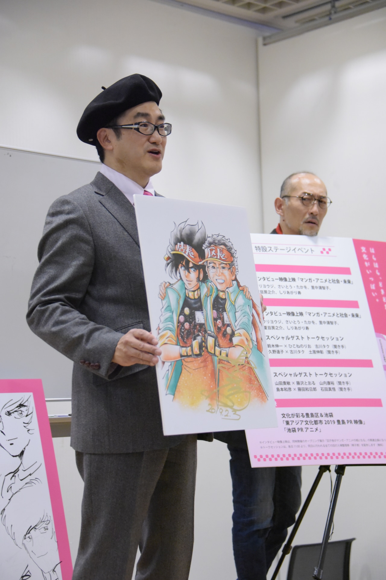 アニメイトの公式キャラクター・アニメ店長と豊島区長のコラボイラストを手にする島本和彦（左）と、それを見つめる藤田和日郎（右）。