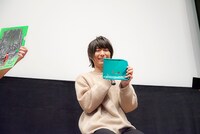 展覧会「モブサイコ100 II EXHIBITION」で発売中のグッズを手にする伊藤節生。