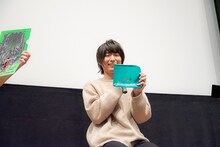 展覧会「モブサイコ100 II EXHIBITION」で発売中のグッズを手にする伊藤節生。