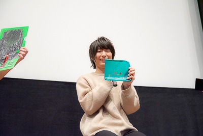 展覧会「モブサイコ100 II EXHIBITION」で発売中のグッズを手にする伊藤節生。