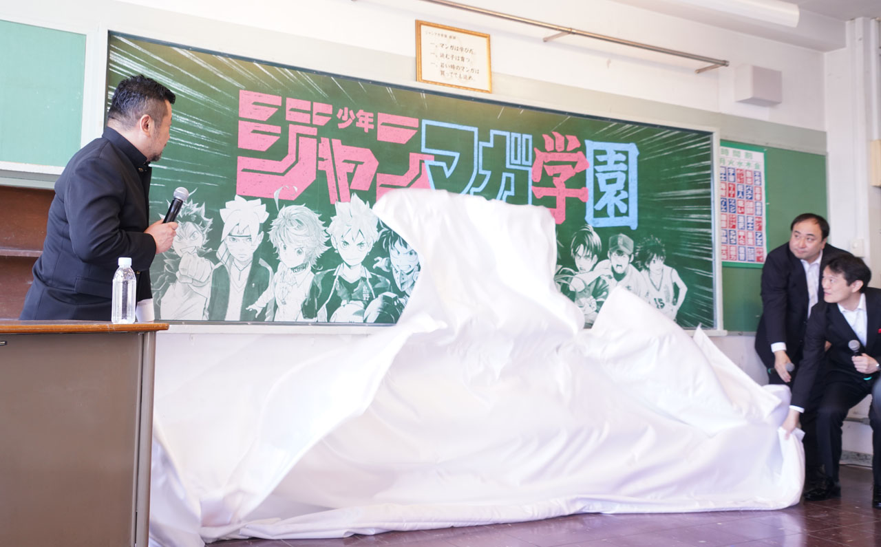 黒板に描かれたビジュアルの除幕を行う登壇者。