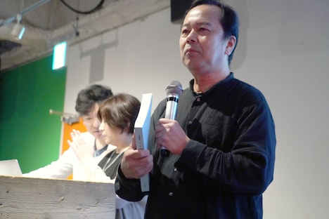 台本の分厚さを紹介する諏訪道彦プロデューサー。
