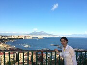 ヴェスビオ山をバックにリポートするミステリーハンターの華恵。