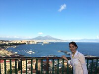 ヴェスビオ山をバックにリポートするミステリーハンターの華恵。