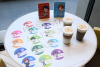 同ビル1階のカフェで提供されるラテアートと、ノベルティのコースター。