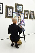 「画業30周年記念小畑健展 NEVER COMPLETE」のビジュアルにサインを入れる小畑健。
