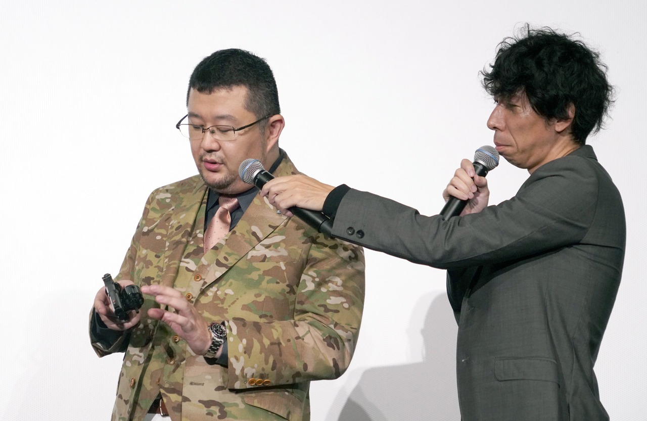 モデルガンを使ってリロードについて説明する金子賢一（左）。
