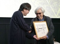 高橋陽一（左）からイラストを手渡される山田洋次監督（右）。