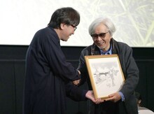 高橋陽一（左）からイラストを手渡される山田洋次監督（右）。
