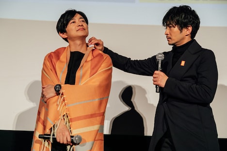 再販が決定した「ジーンのブランケット」を巻きつける下野紘（左）と津田健次郎（右）。