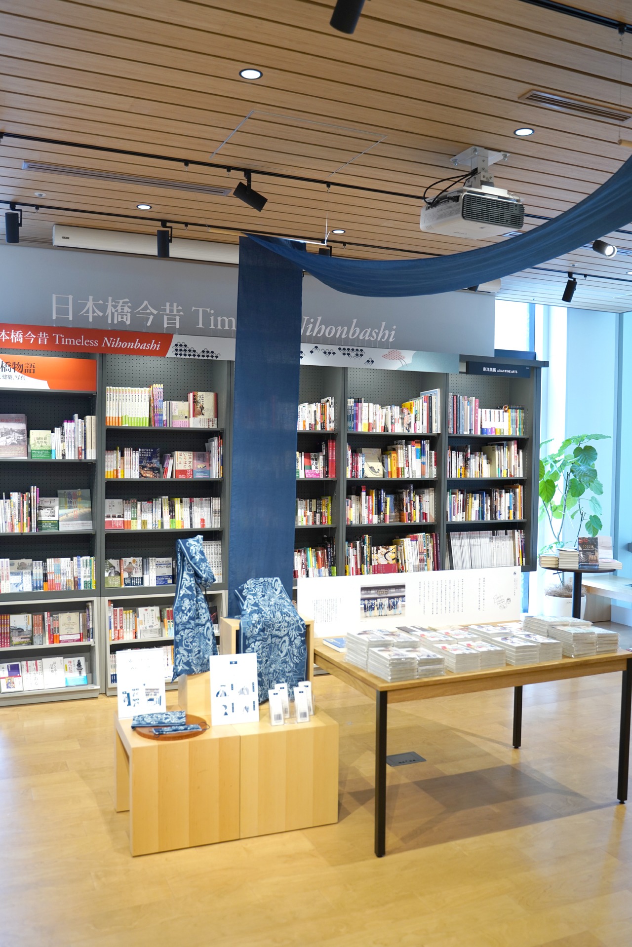 「日に流れて橋に行く」単行本やマスク、手ぬぐいの展示コーナー。
