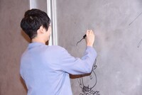 ロビー壁面にサインを書き入れる梶裕貴。