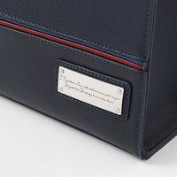 「川嶋 亜美 モデル 2wayショルダートートバッグ」のプレート。亜美のセリフ「同じ道の上の、少し先を歩いていくよ」の英訳がデザインされている。