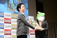 左から「葬送のフリーレン」の担当編集を務める小倉功雅氏と山口つばさ。記念品のプライズが贈呈される様子。