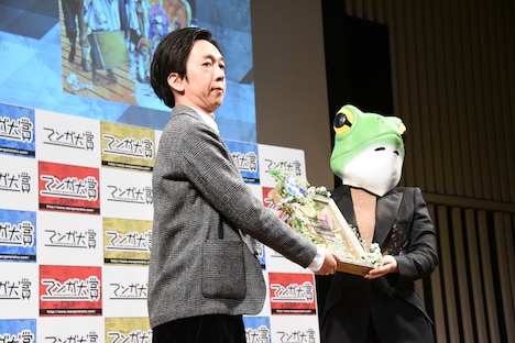 左から「葬送のフリーレン」の担当編集を務める小倉功雅氏と山口つばさ。記念品のプライズが贈呈される様子。