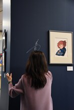 「『アニメージュとジブリ展』一冊の雑誌からジブリは始まった」メディア向け先行内覧会より、会場の壁にサインを入れる島本須美。