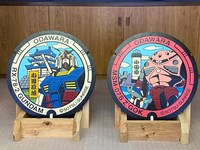 「ガンダム マンホール」（左）と「シャア専用ズゴック マンホール」（右）。