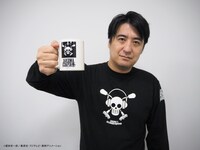 コラボグッズのマグカップを掲げる佐久間宣行。