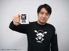 コラボグッズのマグカップを掲げる佐久間宣行。