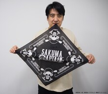 コラボグッズのバンダナを広げる佐久間宣行。