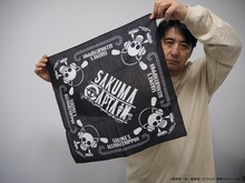 コラボグッズのバンダナを広げる佐久間宣行。