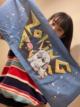 「ノリノリな2人のマフラータオル」を広げるアイナ・ジ・エンド。