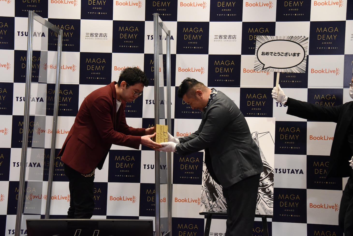 ガッツの代理出席者として登壇したヤングアニマル（白泉社）編集部主任の高村亮氏がトロフィーを受け取る様子。