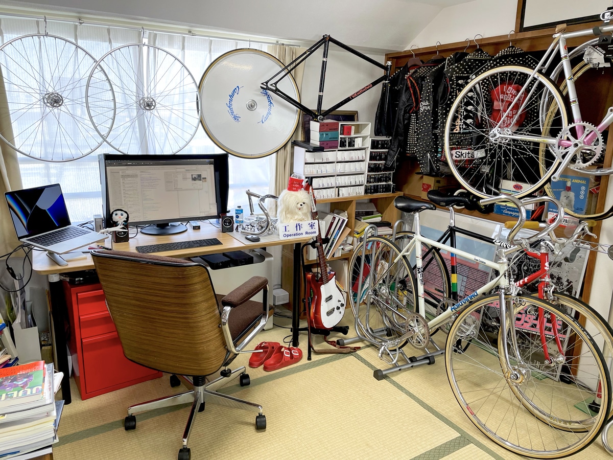 趣味の自転車、鋲ジャン、ギターなどに囲まれたワークスペース。「畳は疲れたらすぐに寝転べるのが最高」と語っていた。