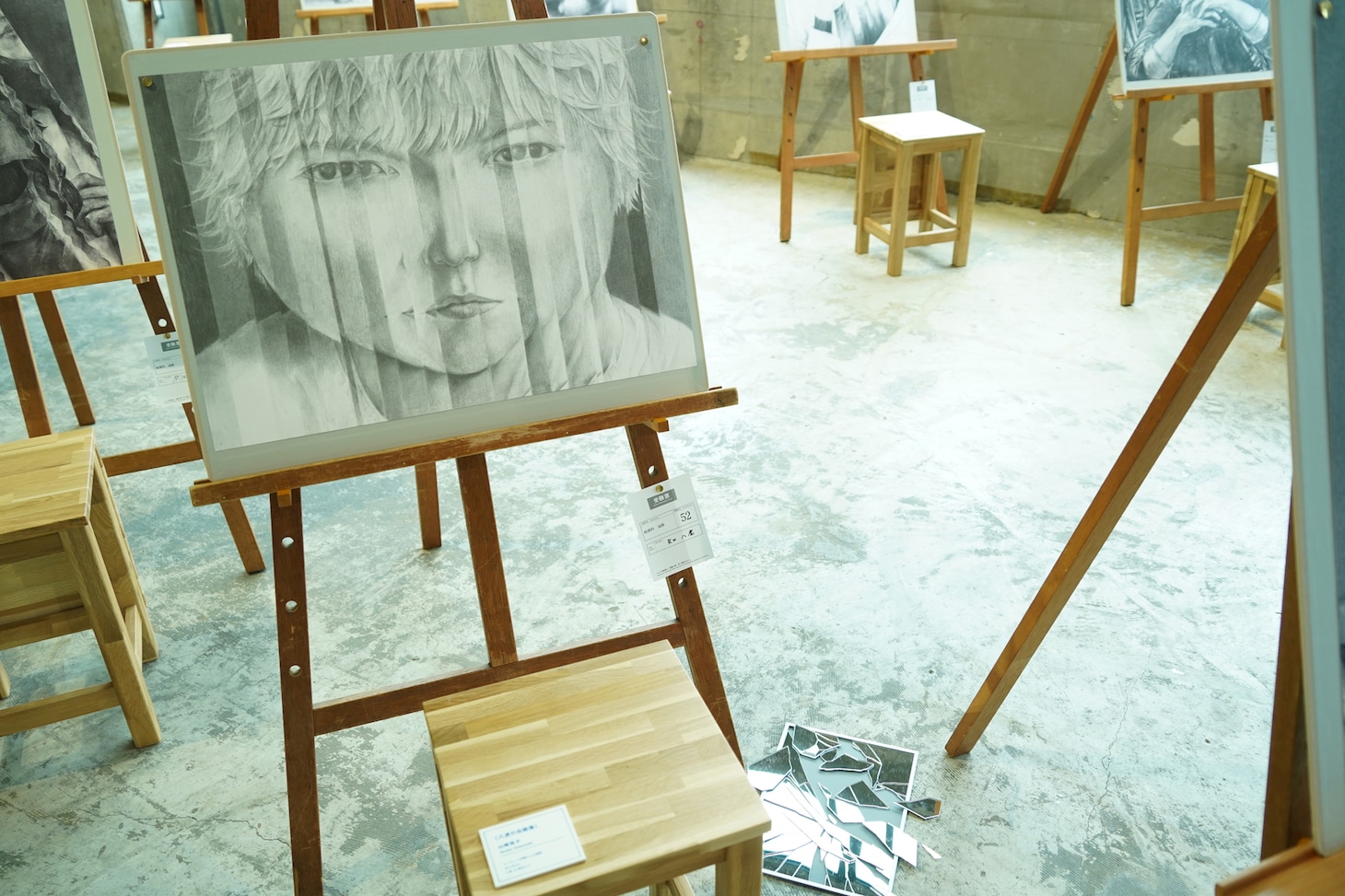 「1次試験『自画像』」コーナーで展示されている八虎の作品。足元には割れた鏡が落ちている。