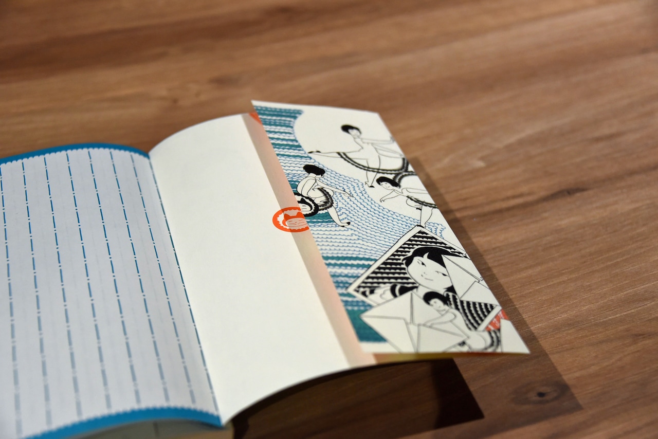 ガンダレになっている表紙が折り返された様子。先ほど話題に出ていた、表紙が折り返した袖の部分と表2で合わさるシール風のイラストも確認できる。