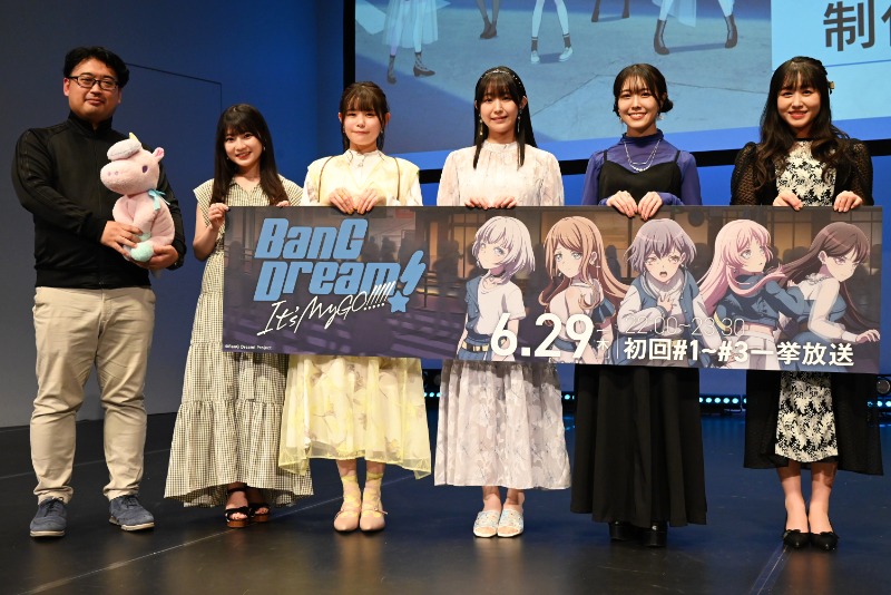 左から柿本広大監督と綾奈ゆにこの代理のユニコーンのぬいぐるみ、青木陽菜、小日向美香、羊宮妃那、立石凛、林鼓子。