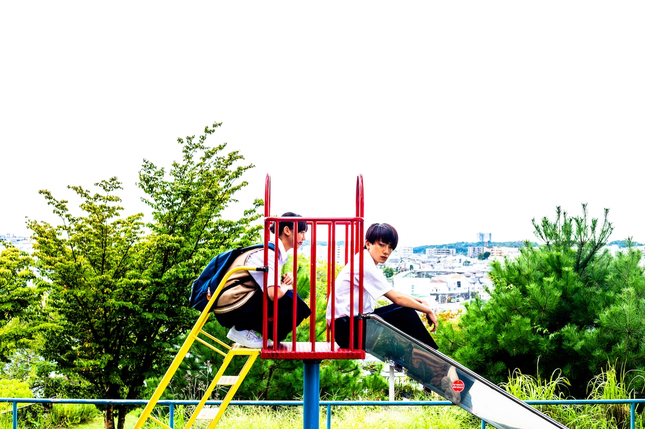 映画「尾かしら付き。」メインカットと場面写が公開、滑り台の上で話す宇津見＆那智