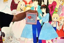 オリジナルグッズのゴーフレットを紹介する菅良太郎。 (c)池野恋／集英社