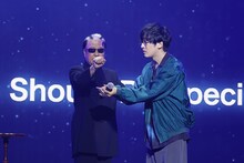 スプーンを曲げるMr.マリックと、まがったスプーンが落ちてきたところを受け止めようとする寺島拓篤。