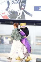 バッドばつ丸と肩を組んで降壇する松岡洋平。