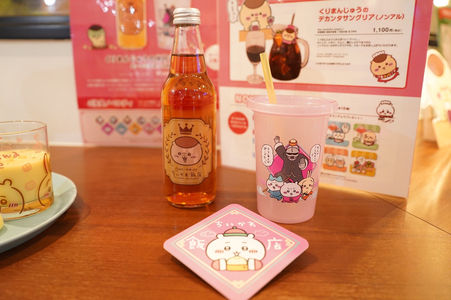 テイクアウトメニューの「」くりまんじゅうの休館日ドリンク スーベニアカップ付き。ノベルティのコースターは全17種だ。