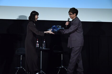 「少佐、おめでとう！」と言って田中敦子（左）に誕生日プレゼントを渡す山寺宏一（右）。