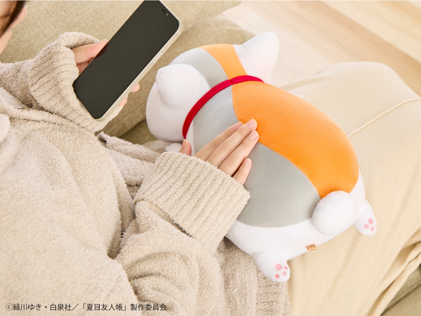 「あったかぬいぐるみ ニャンコ先生」。膝に乗せると愛らしい後ろ足の肉球や、ぷっくりしたおしりが見える。