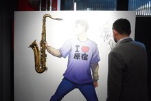 パネルにサインをする石塚真一。