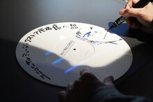 サインをする石塚真一。大と雪祈を描き下ろした。