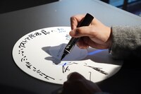 サインをする石塚真一。大と雪祈を描き下ろした。