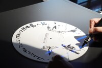 サインをする石塚真一。大と雪祈を描き下ろした。