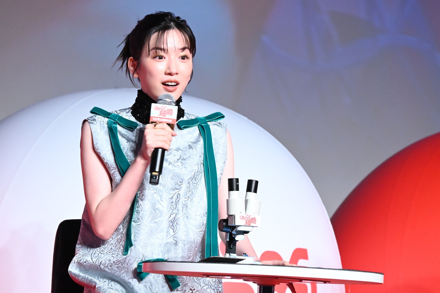 顕微鏡でポスターを見て驚く永野芽郁。