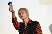 デクのぬいぐるみを掲げながら降壇する岡本信彦。